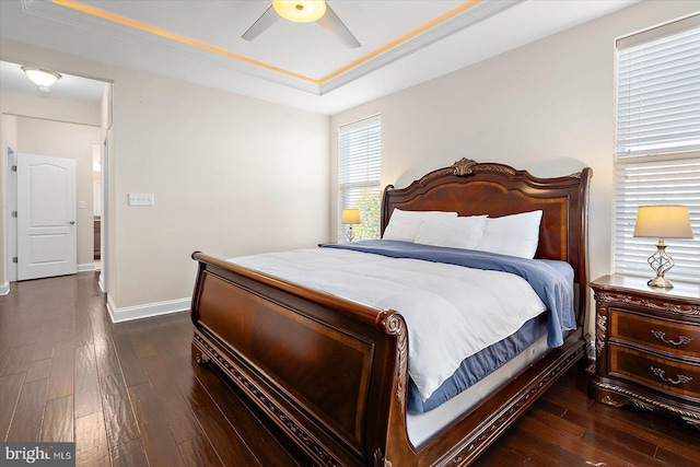 bedroom featuring ceiling fan, dark hardwood / wood-style floors, and a tray ceiling