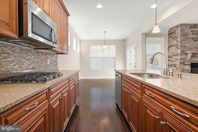 kitchen featuring appliances with stainless steel finishes, light stone counters, hanging light fixtures, and sink