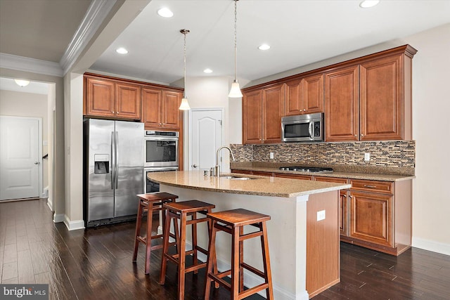 kitchen with light stone counters, sink, a center island with sink, and appliances with stainless steel finishes