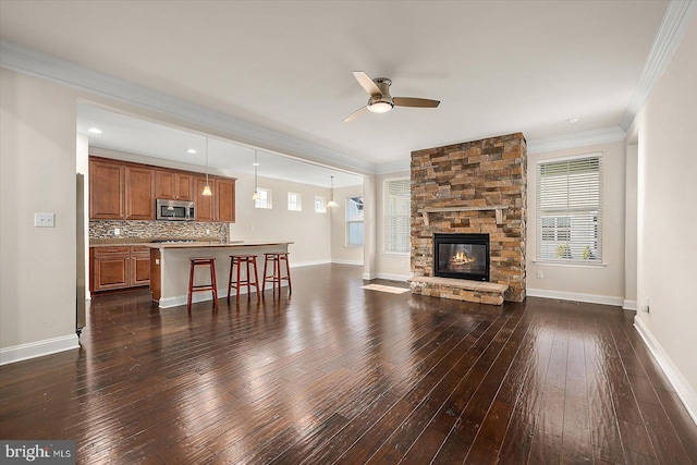 living room with ceiling fan, dark hardwood / wood-style floors, crown molding, and a fireplace