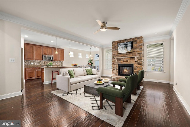 living room with a stone fireplace, ceiling fan, crown molding, and dark hardwood / wood-style flooring