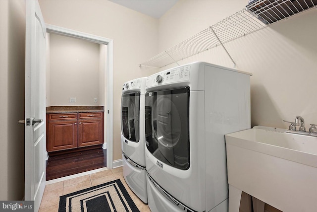 laundry area with washing machine and dryer, light tile patterned floors, and sink