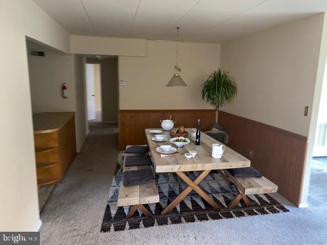 carpeted dining space featuring wooden walls