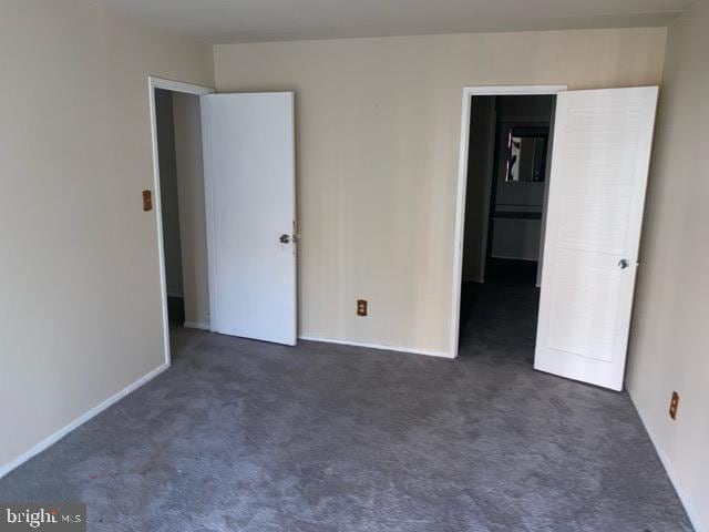 unfurnished bedroom with dark carpet