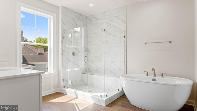 bathroom with hardwood / wood-style floors, vanity, and shower with separate bathtub