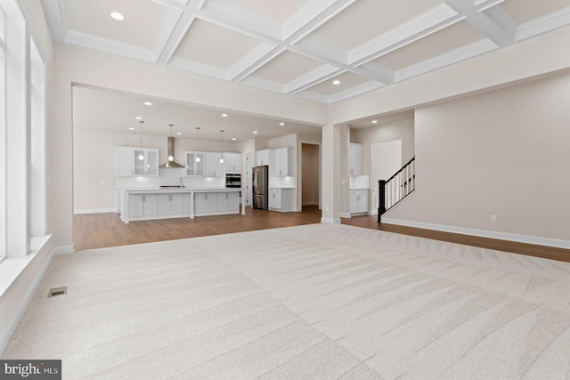 unfurnished living room featuring beam ceiling, light hardwood / wood-style flooring, and coffered ceiling