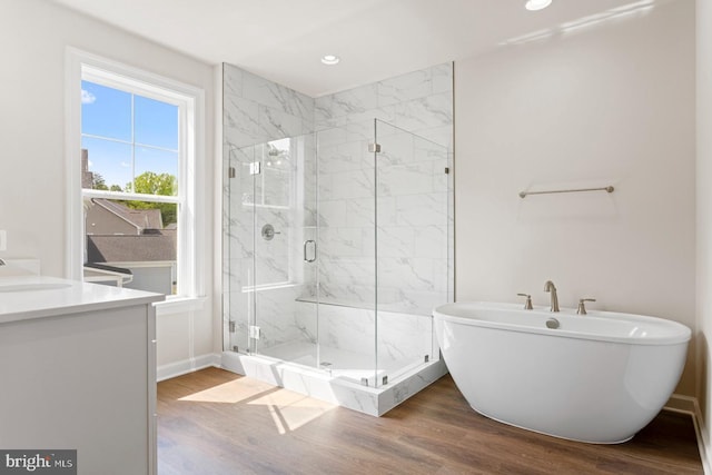 bathroom featuring hardwood / wood-style flooring, vanity, and separate shower and tub