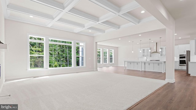 unfurnished living room featuring sink, beamed ceiling, coffered ceiling, and hardwood / wood-style flooring