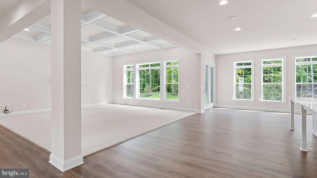 unfurnished living room with beam ceiling, dark hardwood / wood-style floors, a wealth of natural light, and coffered ceiling