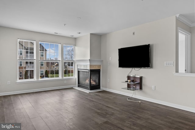 unfurnished living room featuring a multi sided fireplace, dark wood-type flooring, and ornamental molding