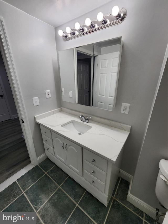 bathroom with toilet, vanity, and tile patterned floors