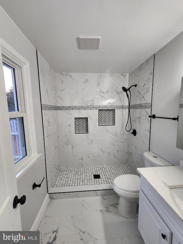 bathroom featuring vanity, toilet, and tiled shower