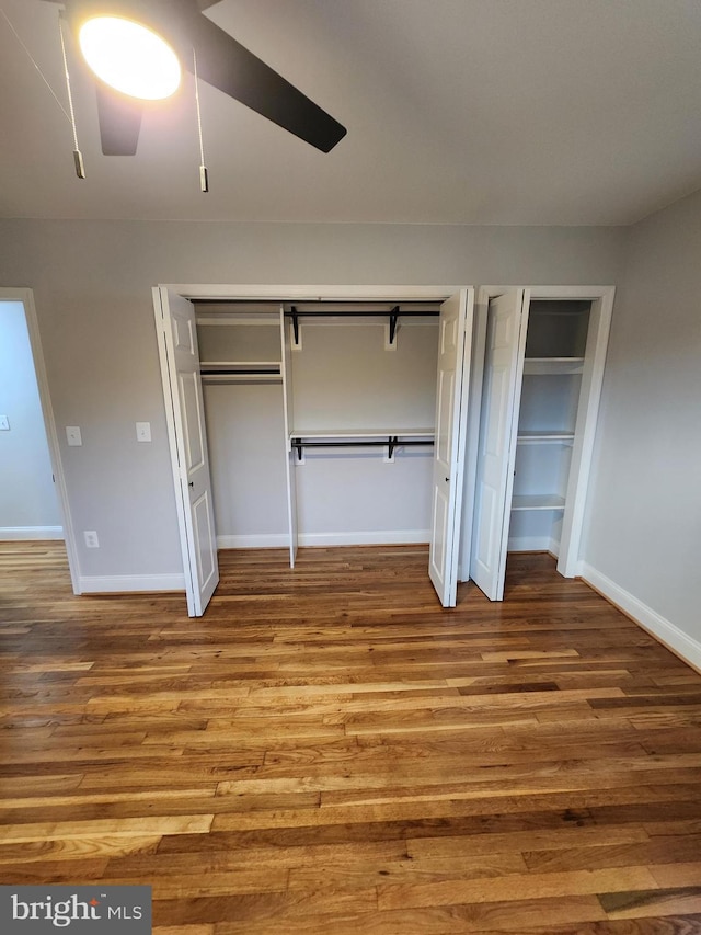 unfurnished bedroom featuring two closets, light hardwood / wood-style floors, and ceiling fan