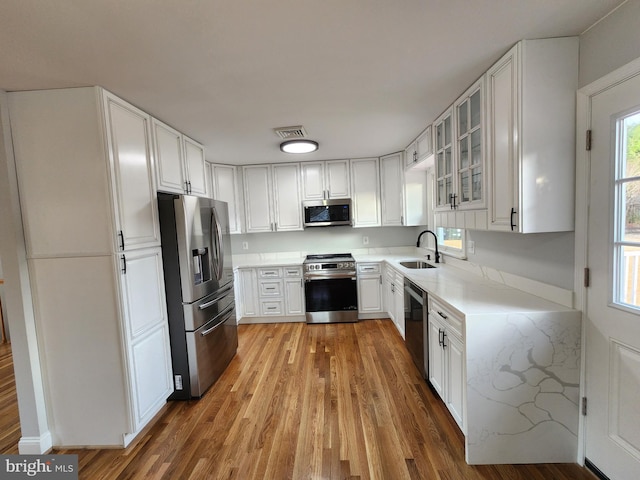 kitchen featuring white cabinets, light wood-type flooring, stainless steel appliances, and sink