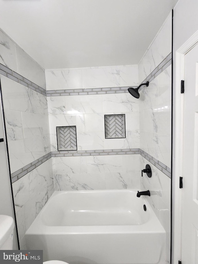 bathroom featuring tiled shower / bath combo and toilet