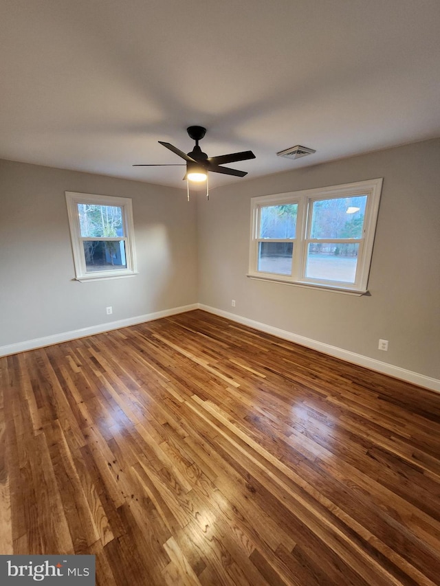 unfurnished room with a wealth of natural light, hardwood / wood-style floors, and ceiling fan