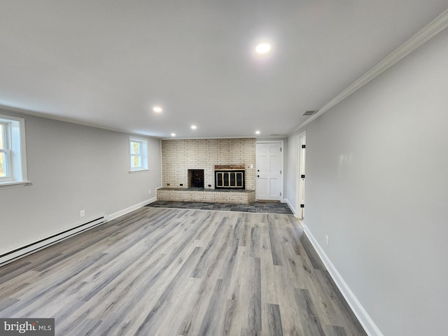 unfurnished living room with crown molding, light hardwood / wood-style flooring, a baseboard heating unit, and a brick fireplace