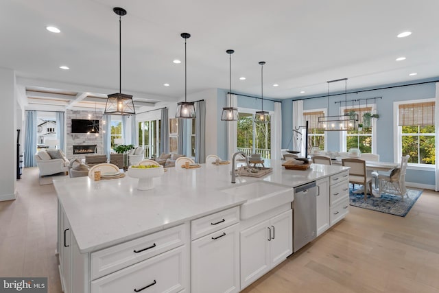 kitchen featuring white cabinets, a large fireplace, a spacious island, pendant lighting, and dishwasher