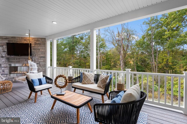 wooden terrace with an outdoor living space with a fireplace