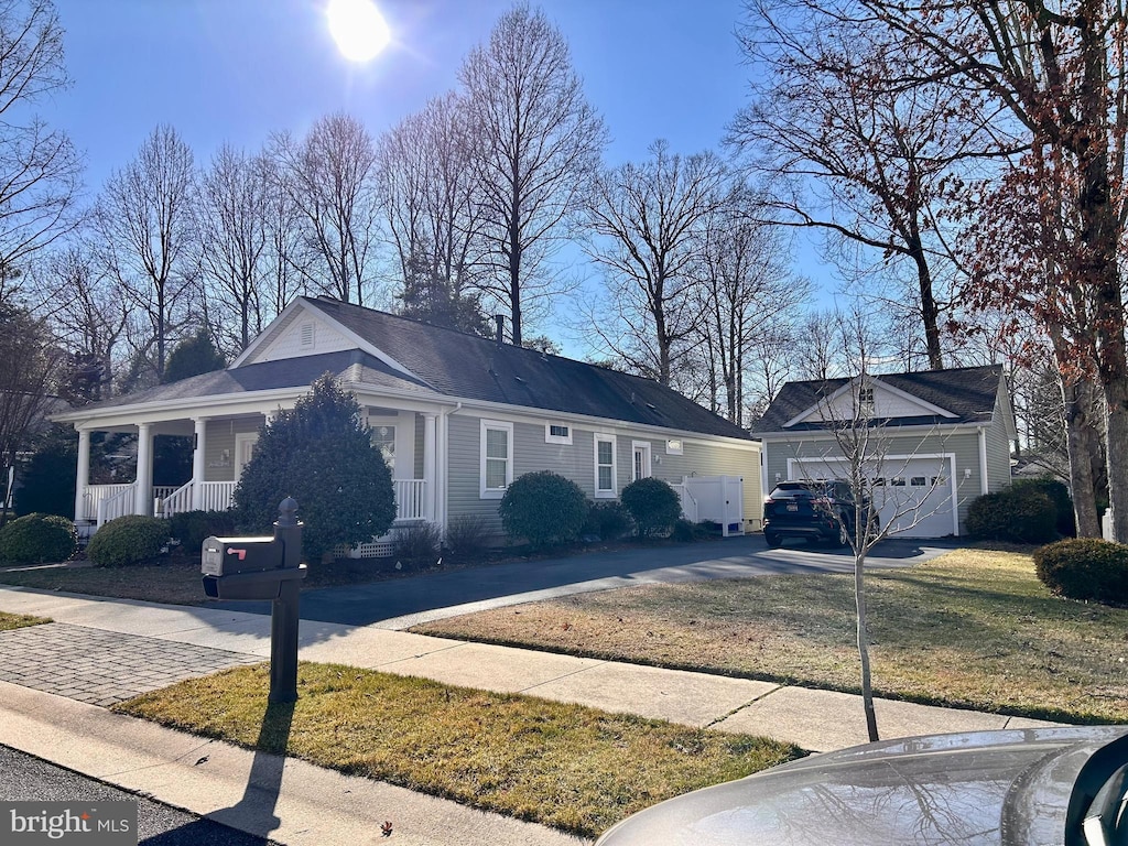 view of front of home featuring a garage, an outbuilding, a porch, and driveway