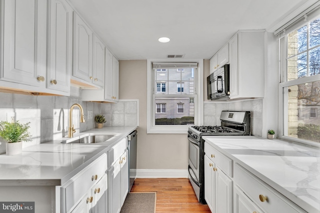 kitchen featuring decorative backsplash, white cabinetry, light hardwood / wood-style floors, and appliances with stainless steel finishes