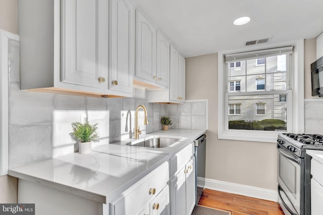 kitchen with hardwood / wood-style floors, white cabinetry, sink, and appliances with stainless steel finishes