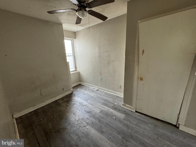 empty room featuring ceiling fan, a textured ceiling, and dark wood-type flooring