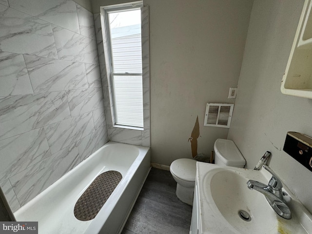 bathroom with a tub, vanity, and toilet