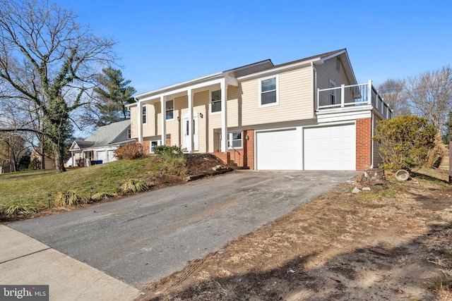 split foyer home featuring a garage, a balcony, and a front lawn