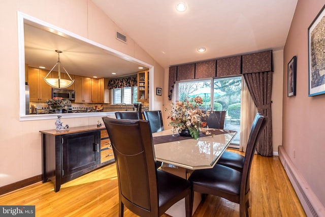 dining room featuring light hardwood / wood-style floors, lofted ceiling, sink, and a baseboard heating unit