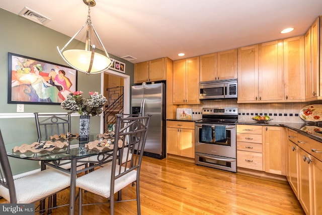 kitchen with backsplash, stainless steel appliances, pendant lighting, light brown cabinets, and light hardwood / wood-style floors