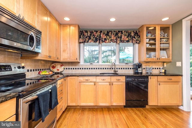 kitchen with dark stone counters, sink, light hardwood / wood-style flooring, and appliances with stainless steel finishes