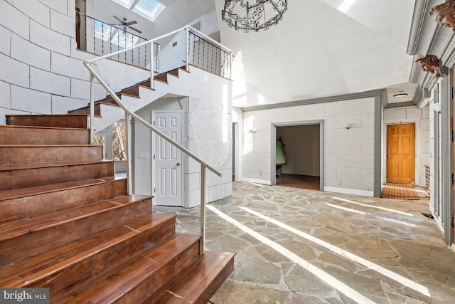 stairway featuring ceiling fan, high vaulted ceiling, and a skylight