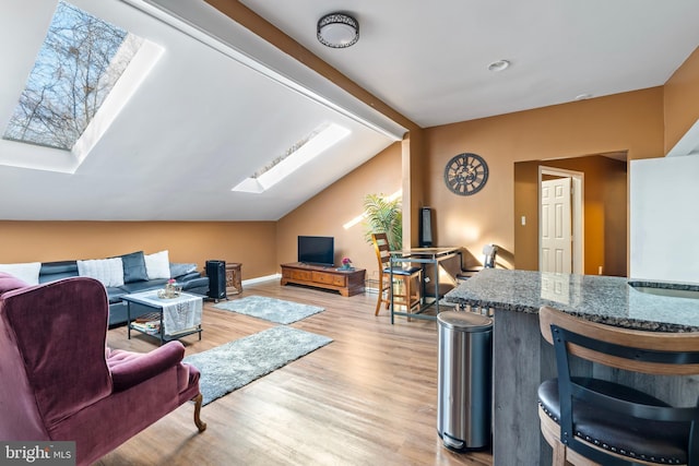 living room with light hardwood / wood-style floors and lofted ceiling with skylight