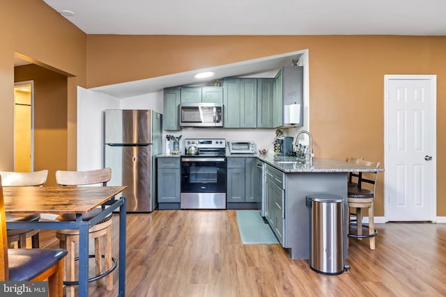 kitchen with stainless steel appliances, light stone counters, light hardwood / wood-style floors, and sink