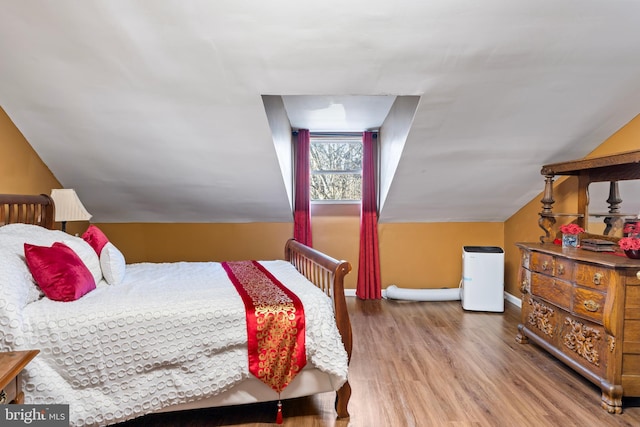 bedroom with hardwood / wood-style flooring and lofted ceiling