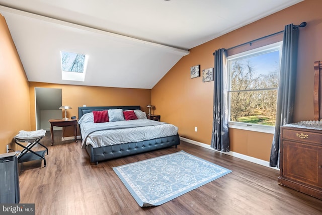 bedroom with vaulted ceiling with skylight and hardwood / wood-style flooring