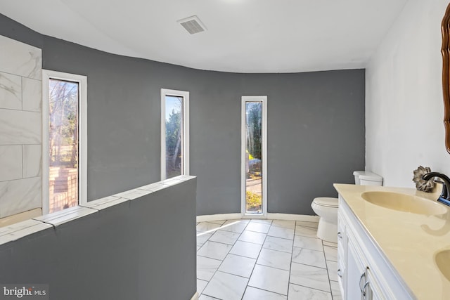 bathroom with vanity, a healthy amount of sunlight, and toilet