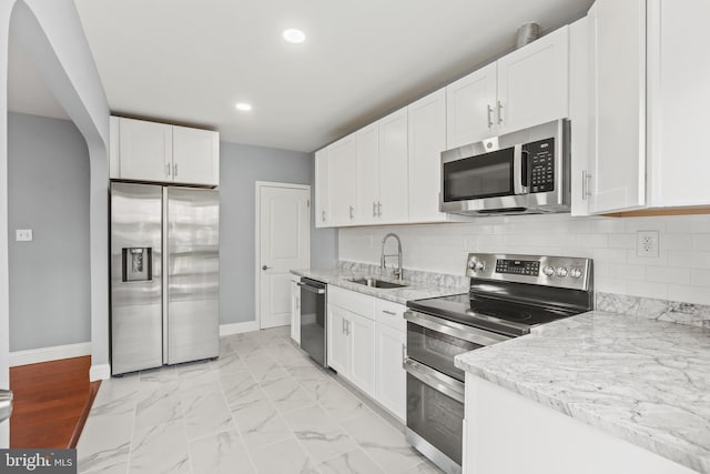 kitchen featuring light stone counters, white cabinetry, sink, and appliances with stainless steel finishes