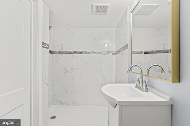 bathroom featuring tiled shower and vanity