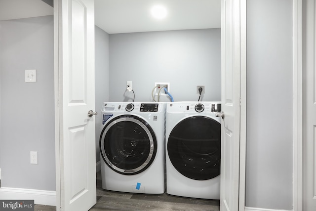 clothes washing area featuring washing machine and clothes dryer and dark hardwood / wood-style flooring