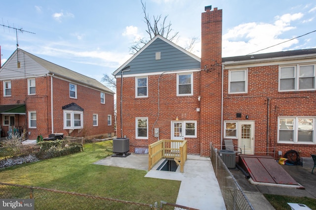 rear view of property with central AC unit and a yard