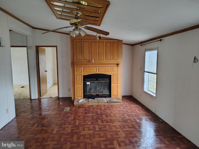 unfurnished living room with ceiling fan, ornamental molding, a large fireplace, and dark parquet flooring