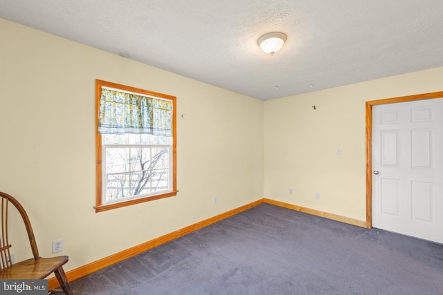 unfurnished room featuring a textured ceiling and dark colored carpet