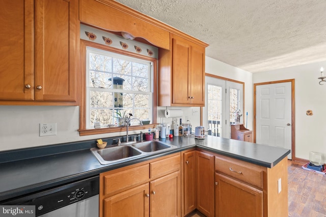 kitchen with sink, light hardwood / wood-style flooring, stainless steel dishwasher, kitchen peninsula, and a textured ceiling