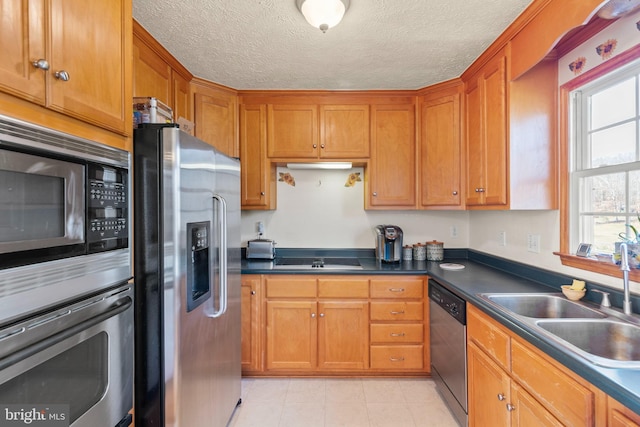 kitchen with sink, a textured ceiling, and appliances with stainless steel finishes