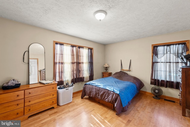 bedroom with light hardwood / wood-style floors and a textured ceiling