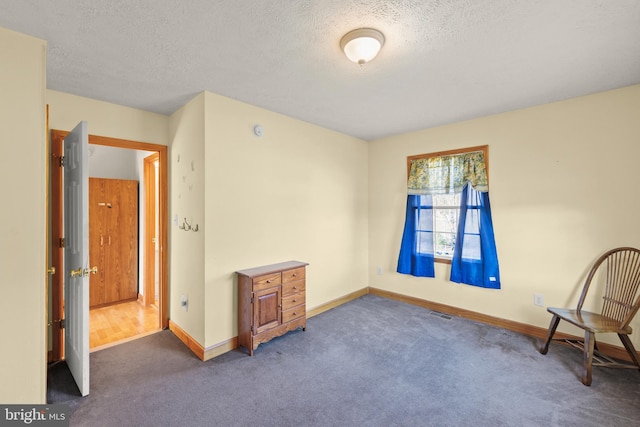 spare room featuring dark colored carpet and a textured ceiling