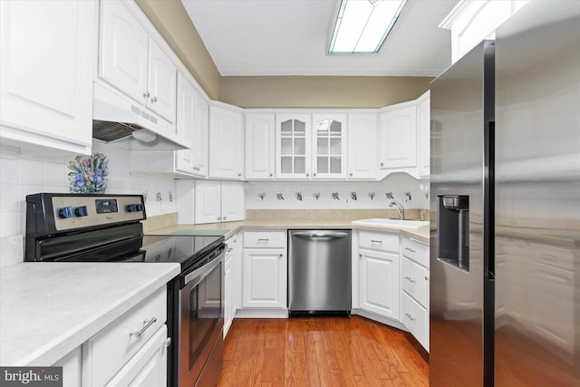 kitchen featuring sink, light hardwood / wood-style flooring, backsplash, white cabinets, and appliances with stainless steel finishes