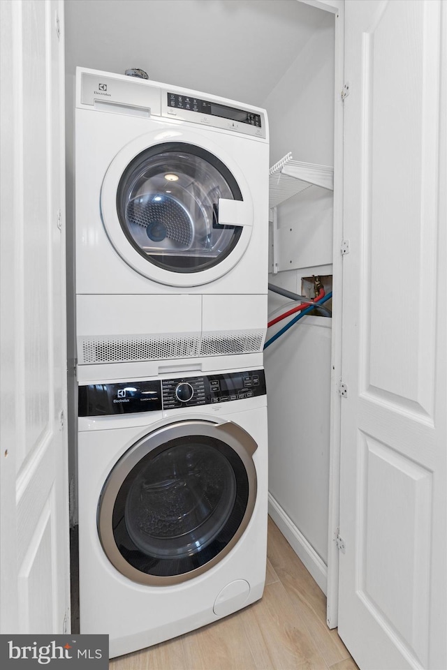 clothes washing area featuring stacked washing maching and dryer